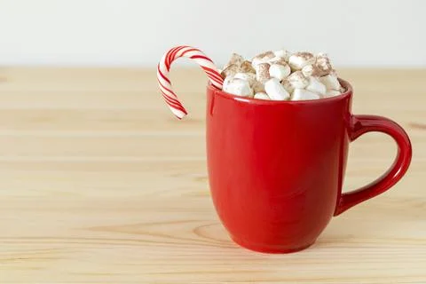 Cocoa in red mug with marshmallows and candy cane on table. Holiday drink, hot Stock Photos