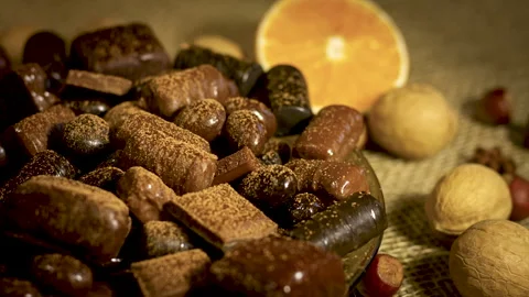 Cocoa sprinkles on top of assorted chocolates, nuts and citrus fruits Stock Footage 131624012