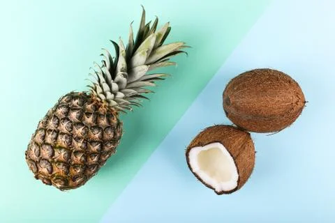 Coconut and pineapple on a colored background. Summer mood, copy space. Stock Photos
