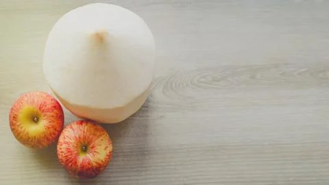 Coconut with apple on cream table Stock Photos