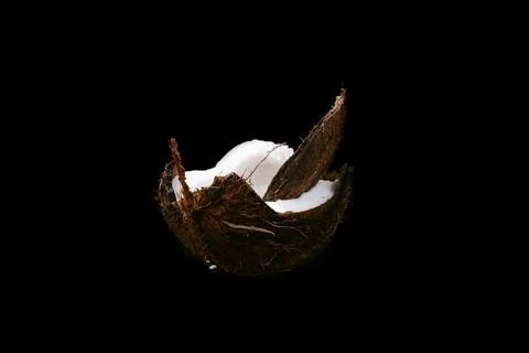 Coconut on a black background isolated. Broken coconut Photos