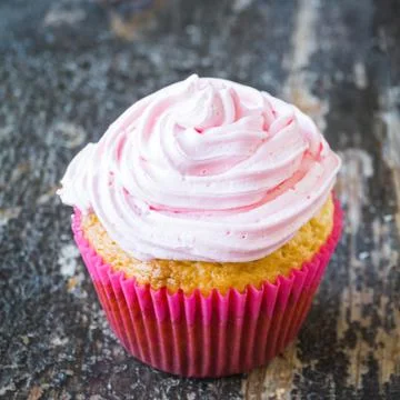 Coconut cupcake with pink curd cream on wooden background Stock Photos