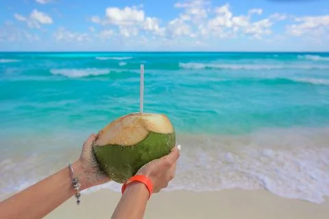 Coconut with drink in hand against the backdrop of the Caribbean sea Stock Photos