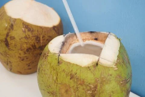 Coconut drink served with a straw on a table Stock Photos