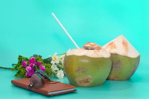 Coconut with drinking straw, notebook and sunglasses on blue background Stock Photos