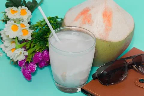 Coconut with drinking straw, notebook and sunglasses on blue background Stock Photos