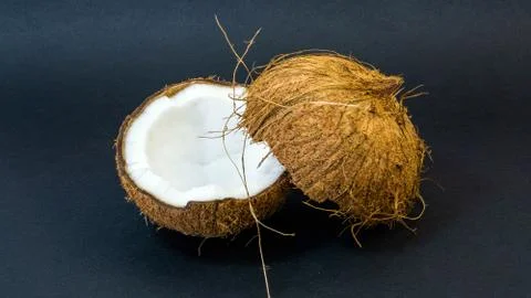 Coconut, exotic fruit, two halves of the fruit in the shell, dark background Stock Photos