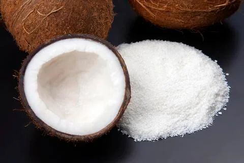 Coconut flakes on a dark background next to a coconut. vitamin fruits. health Stock Photos