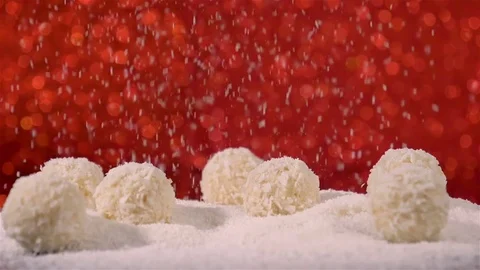 Coconut flakes falling on coconut snowballs white truffles on red background Stock Footage 81014354