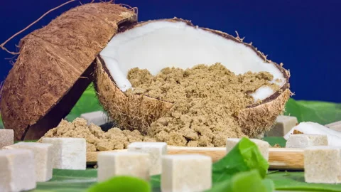 Coconut half, coconut sugar and sugar cubes on green leaves background Stock Footage 89675807