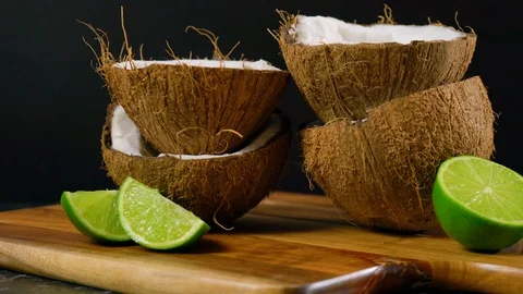 Coconut halves and limes spotlighted against a black background. Stock Footage 124393359