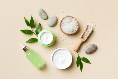 Coconut with jars of coconut oil and cosmetic cream on colored background. To Stock Photos