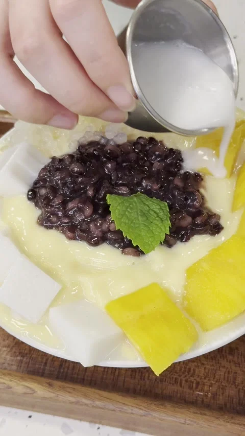 Coconut milk poured over mango sago dessert with red beans Stock-Footage 331179129