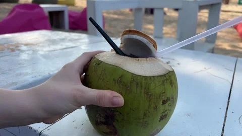 Coconut with non-alcoholic cocktail in hands of relaxed woman on ocean beach Stock Footage 317877652
