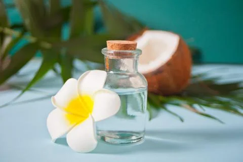 Coconut oil in a bottle with coconuts, flower Plumeria frangipani and green p Photos