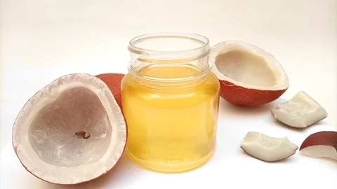 Coconut oil in a jar with coconuts rotating over white background Stock Footage 275670598