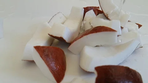 Coconut pieces on white fall, delicious, water pours Stock Footage 87655727