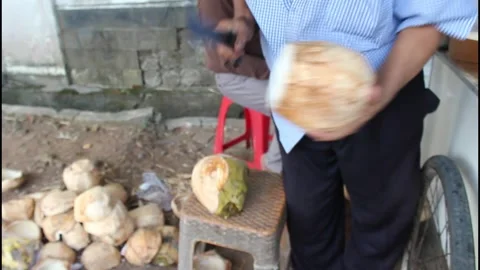 Coconut seller is peeling coconut using cleaver knife Stock Footage 340987707