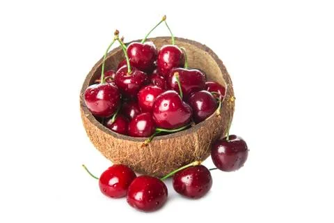 Coconut shell full of cherries on white background Stock Photos