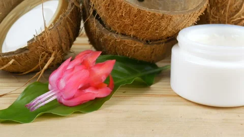 Coconut shells, aloe vera leaves, exotic flowers and cream cosmeticon wooden bac Stock Footage 100663328