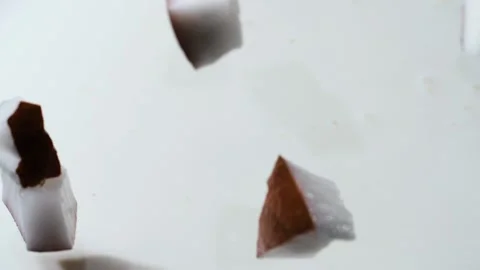 Coconut slices fall into the milk. The spray splashes away. Slow motion. Close-u Stock Footage 144334702