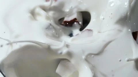 Coconut slices fall into the milk. The spray splashes away. Slow motion. Close-u Stock Footage 144334722
