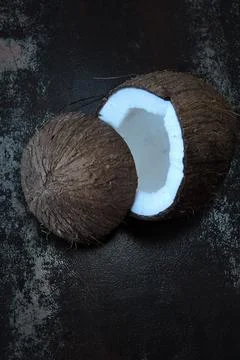 Coconut split in half on a dark shabby surface. Foto stock