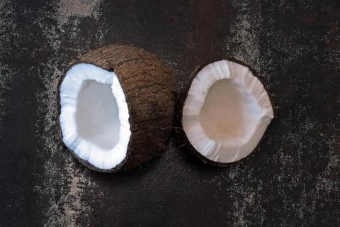 Coconut split in half on a dark shabby surface. Stockfoto's