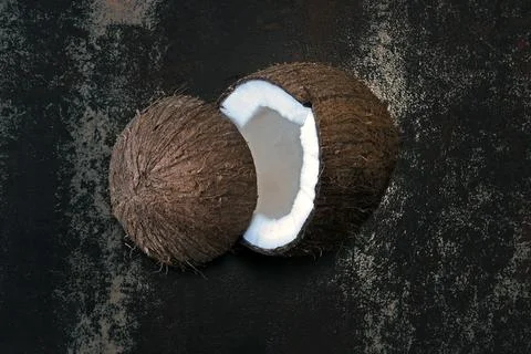 Coconut split in half on a dark shabby surface. Foto stock