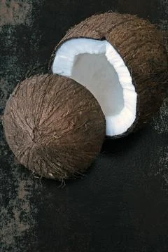 Coconut split in half on a dark shabby surface. Stockfoto's