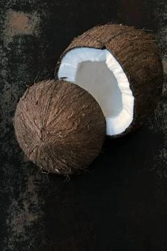 Coconut split in half on a dark shabby surface. Foto stock