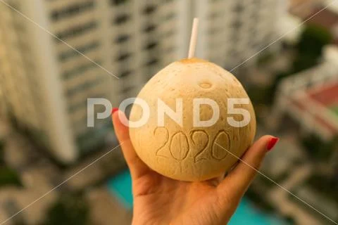 Coconut with straw with 2020 drawing on the beach near the sea Stock Photos