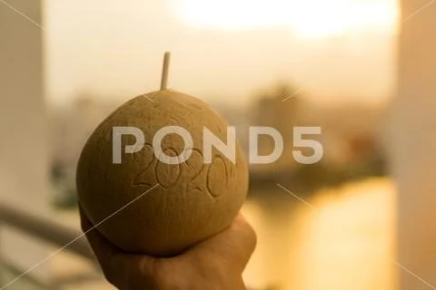 Coconut with straw with 2020 drawing on the beach near the sea Stock Photos