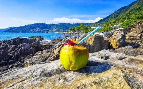 Coconut with straw and flower on rocks at beach mountains. 스톡 사진
