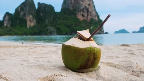 Coconut water drink with a straw on sandy tropical Railay beach with turquoise Stock Footage 282919929