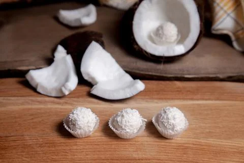 Coconut with white pulp and white candies on wooden background.. Stock Photos