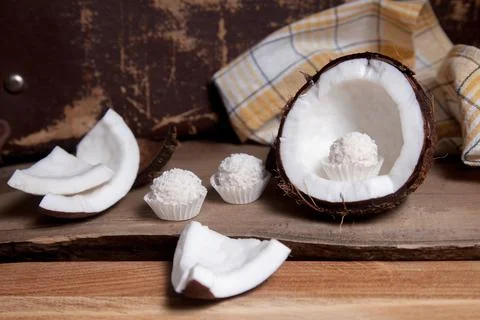Coconut with white pulp and white candies on wooden background.. Stock Photos