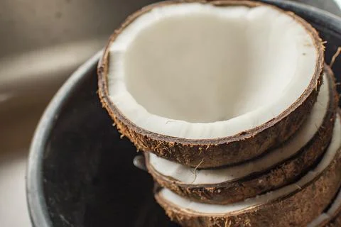 Coconuts are cut into pieces in a container, to make coconut milk. Stock Photos