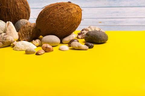 Coconuts, rocks and shells on a blue wooden background and a yellow backgroun Foto stock