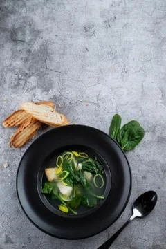 Cod ear soup with fresh spinach and cod pieces on stone background Foto stock