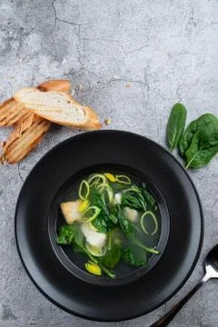 Cod ear soup with fresh spinach and cod pieces on stone background Stock Photos