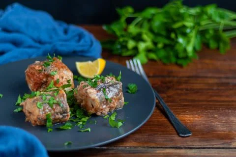 Cod filet or other fish on a gray plate. Braised in tomato and onion. Peas ar Фото