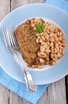 Cod fillet in bread crumbs with baked beans Stock Photos