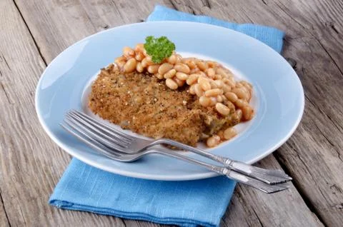Cod fillet in bread crumbs with baked beans Stock Photos