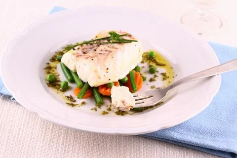 Cod fillet on fork with green beans, peas, parsley, olive oil Stock Photos
