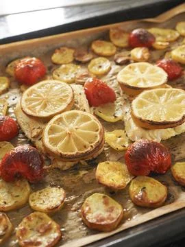 Cod fillet garnished with thyme, garlic and tomatoes, preparation of a healthy Stock Photos