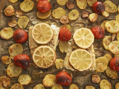 Cod fillet garnished with thyme, garlic and tomatoes, preparation of a healthy Stock Photos