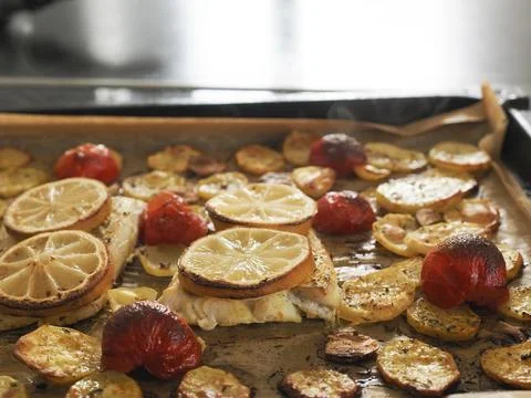 Cod fillet garnished with thyme, garlic and tomatoes, preparation of a healthy Stock Photos