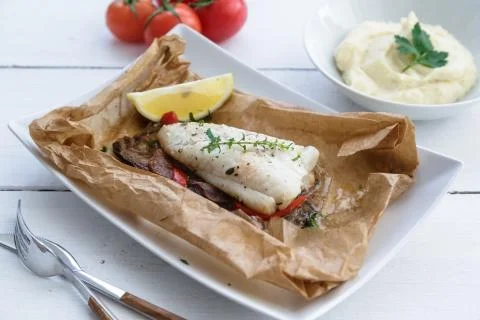 Cod fillets baked in parchment paper with vegetables Stock Photos