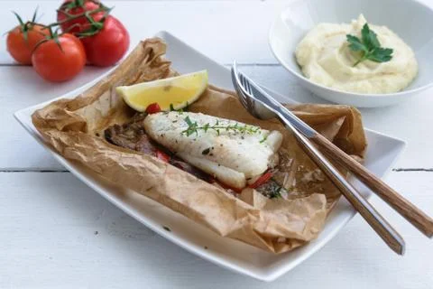 Cod fillets baked in parchment paper with vegetables Stock Photos